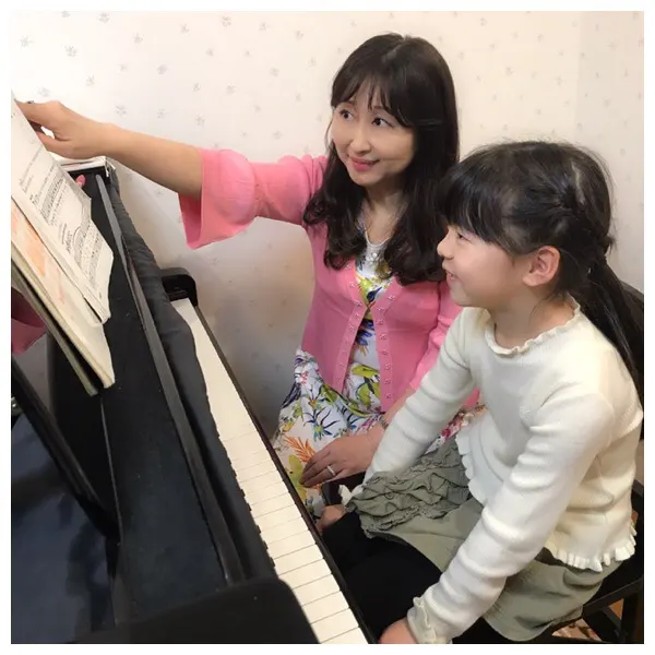講師が生徒さんの横で楽譜を指して教えている様子